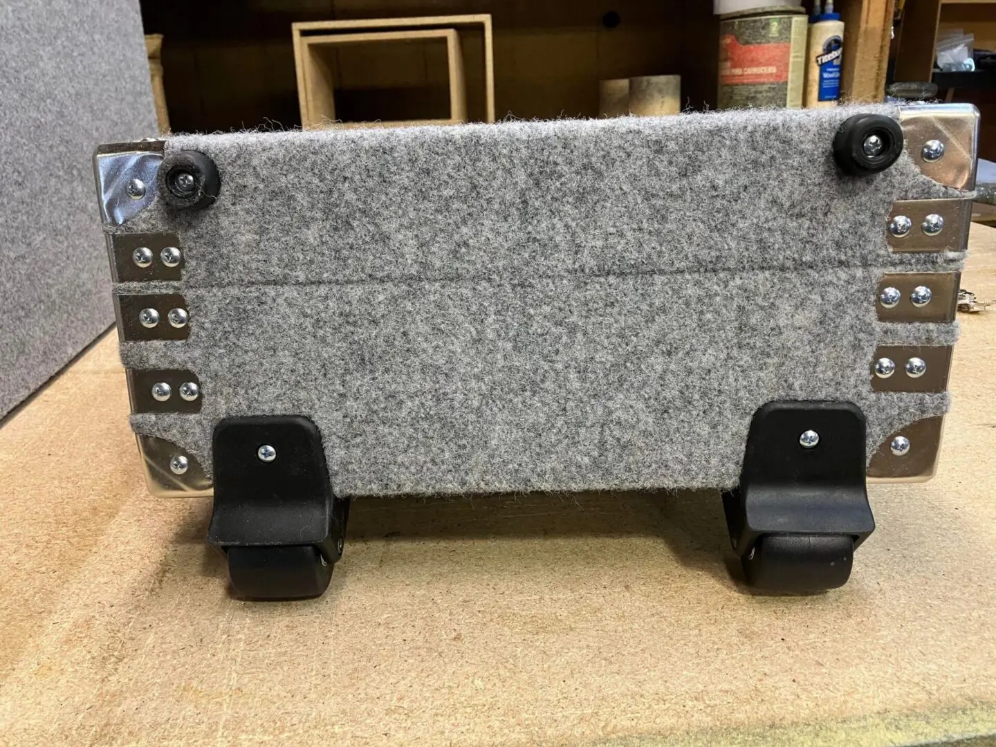 A gray felt Wheeled Case on a workbench.