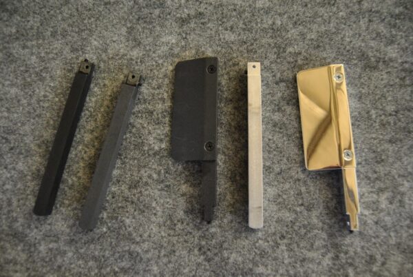 Four different types of metal blades on a grey surface.