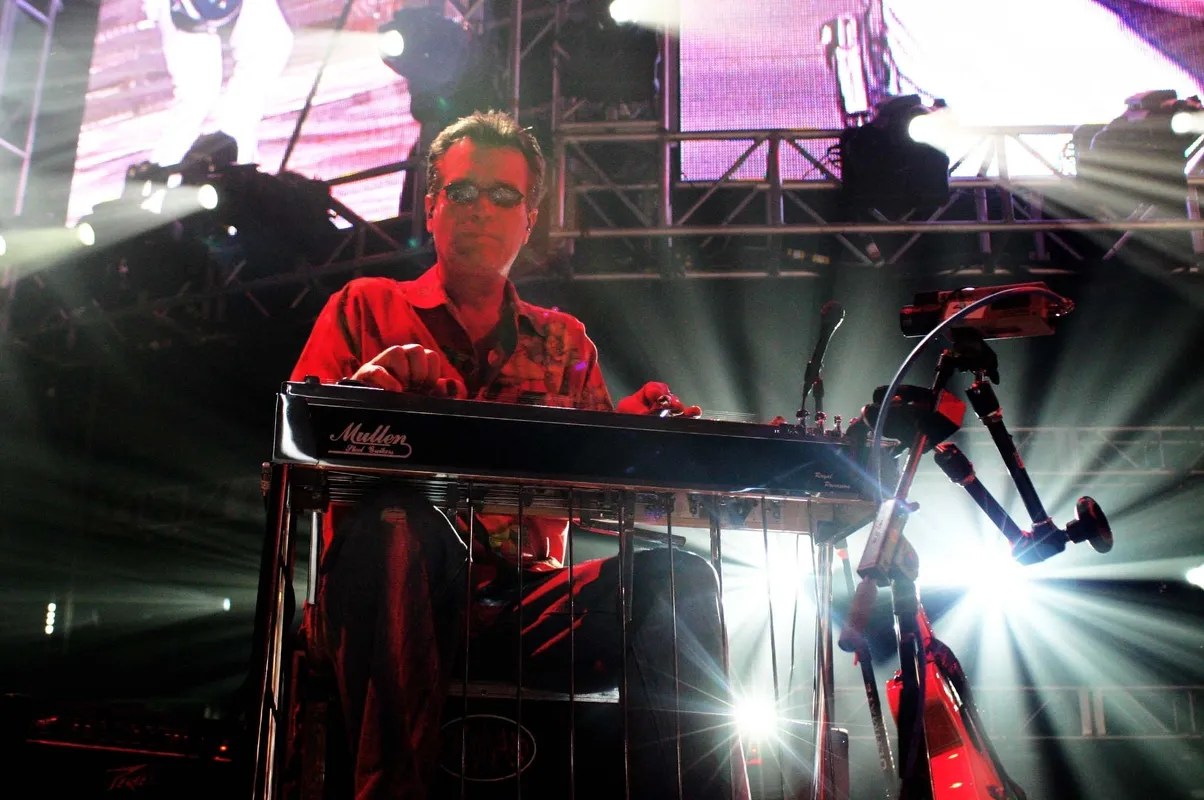 A man in glasses is playing a keyboard on stage.