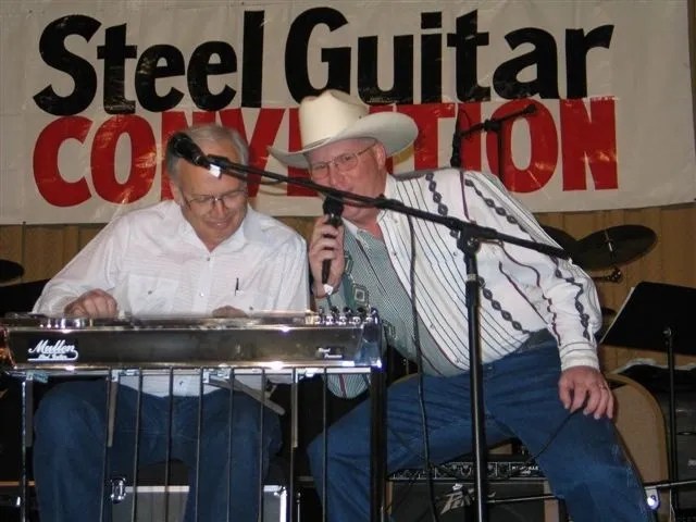 Two men standing next at a steel guitar convention.