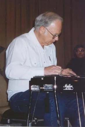 An older man playing a keyboard in front of a group