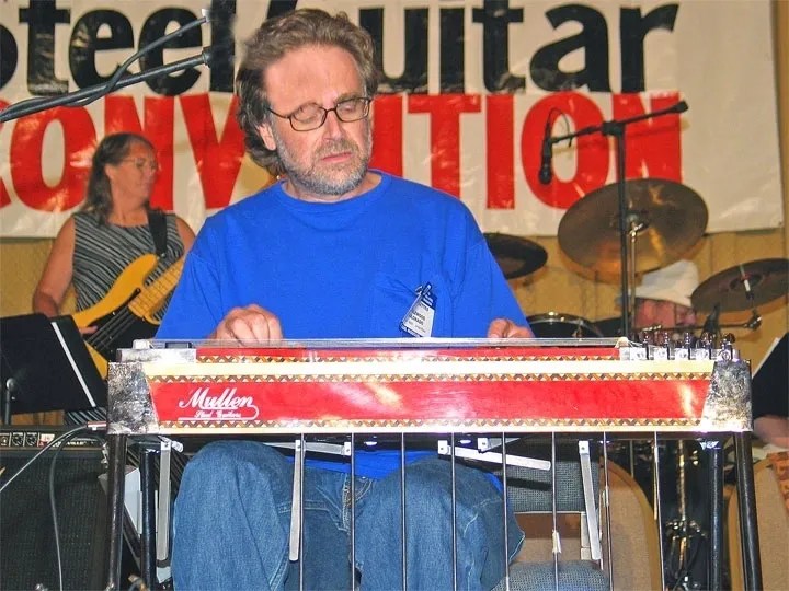 A man playing a steel guitar at a convention.