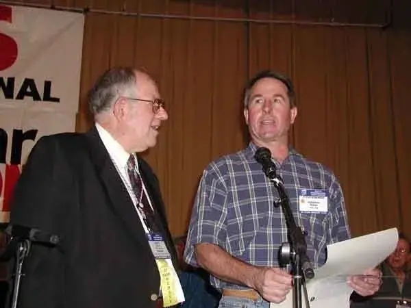Two men standing in front of a microphone.
