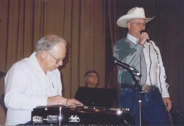 Two men in cowboy hats standing next to a keyboard.